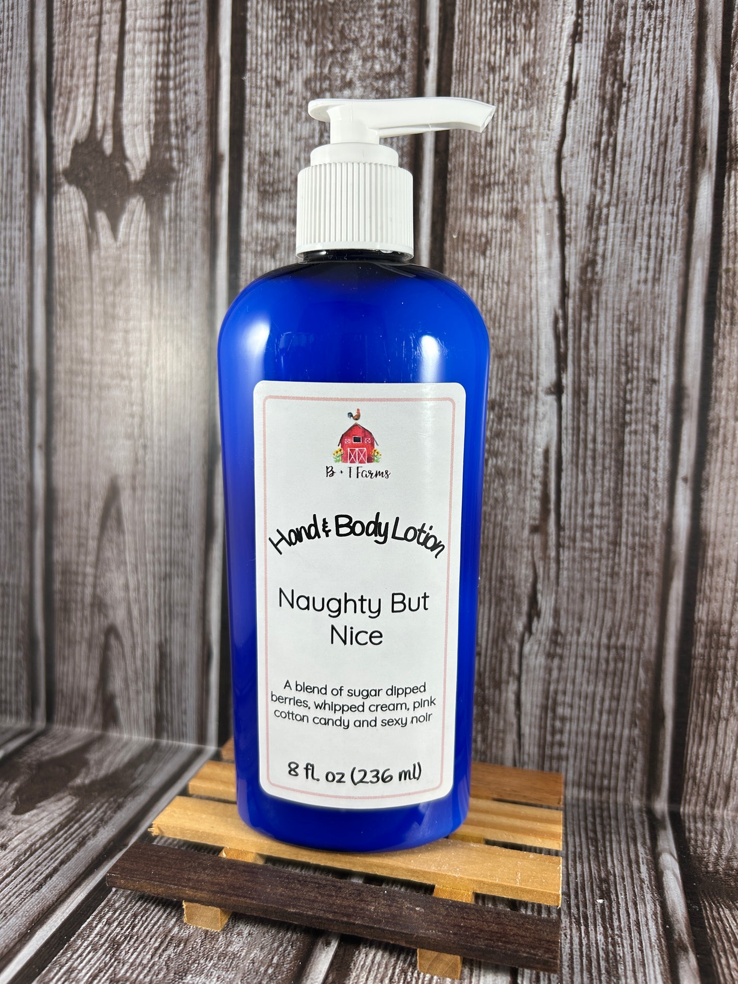 Hand and body lotion bottle on a wooden surface. Scent is called Naughty But Nice.