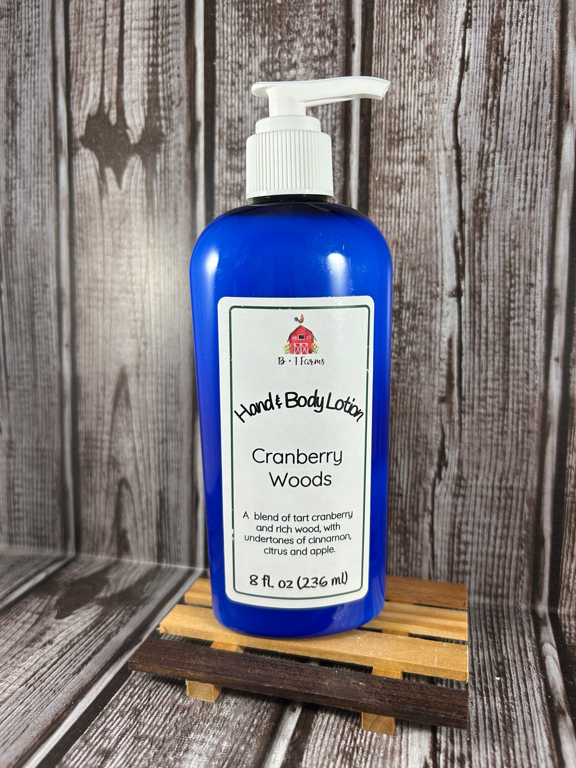 Hand and body lotion bottle on a wooden surface. Scent is called Cranberry Woods