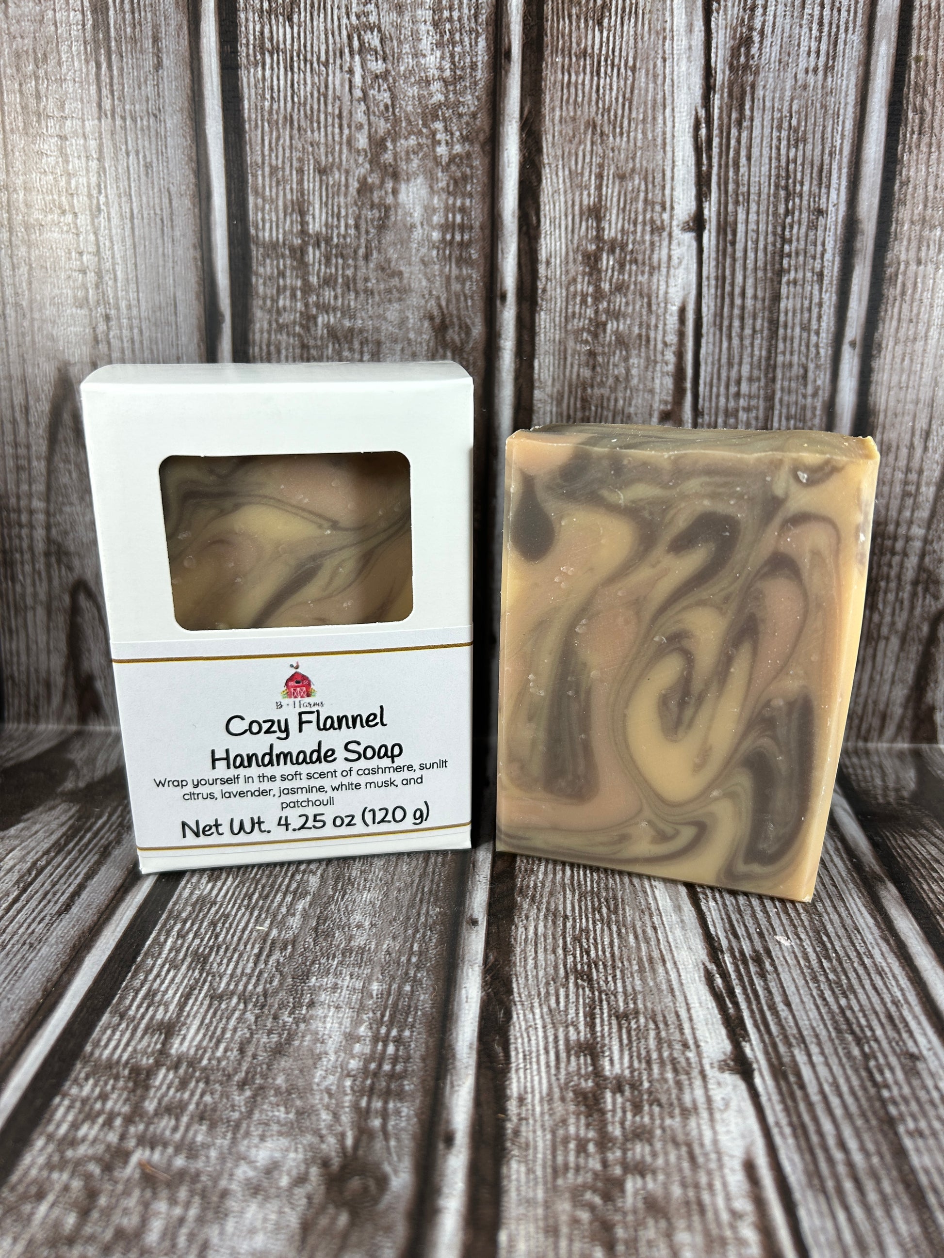 Handmade soap bar with a swirled pattern on a wooden surface, accompanied by its packaging.