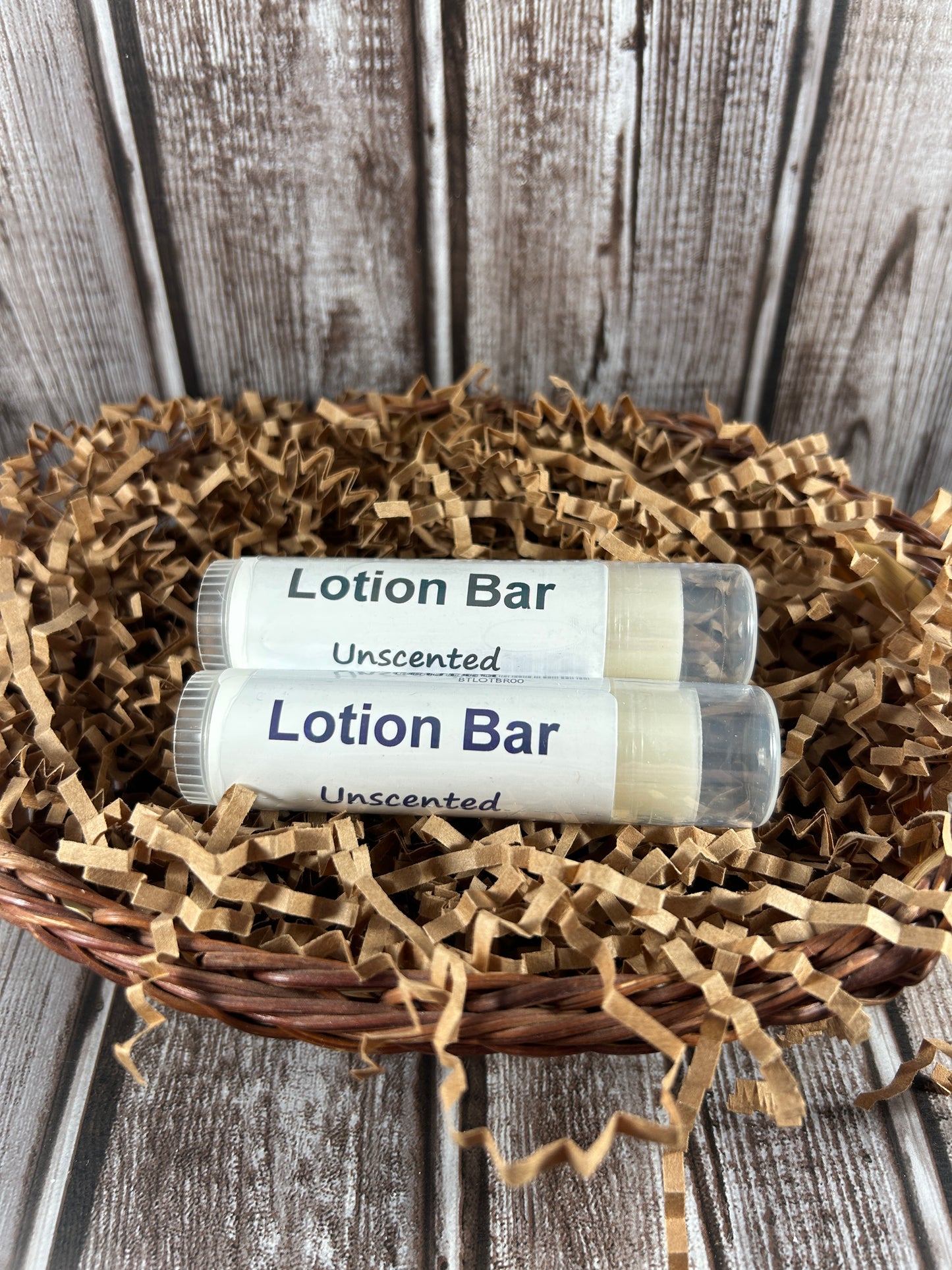 Two lotion bars labeled 'Unscented' on a wooden surface with a decorative wreath.