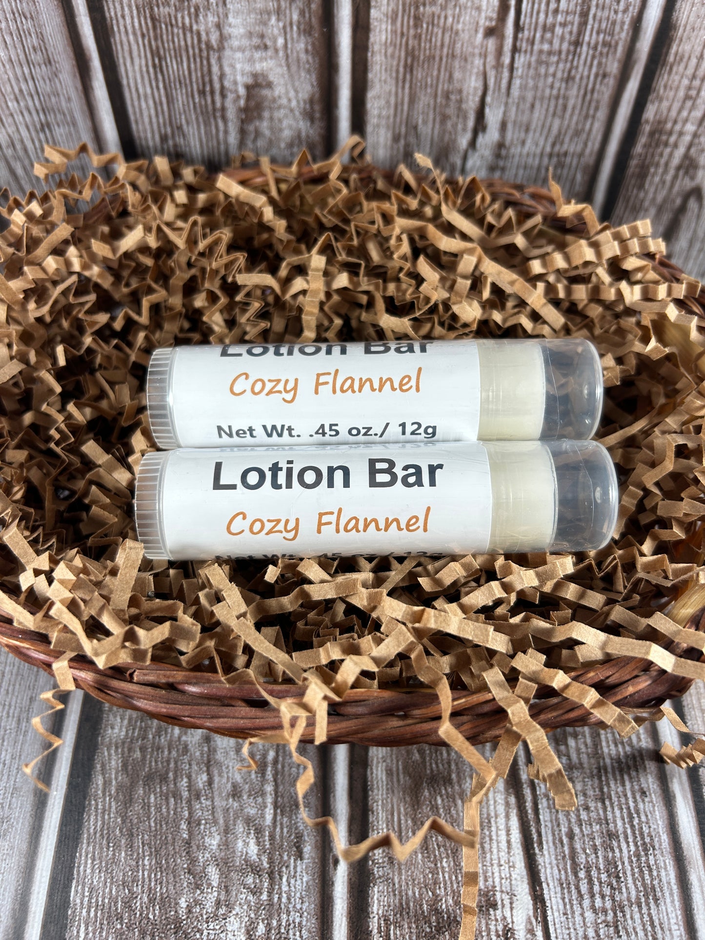 Two Cozy Flannel lotion bars in a decorative wreath on a wooden surface