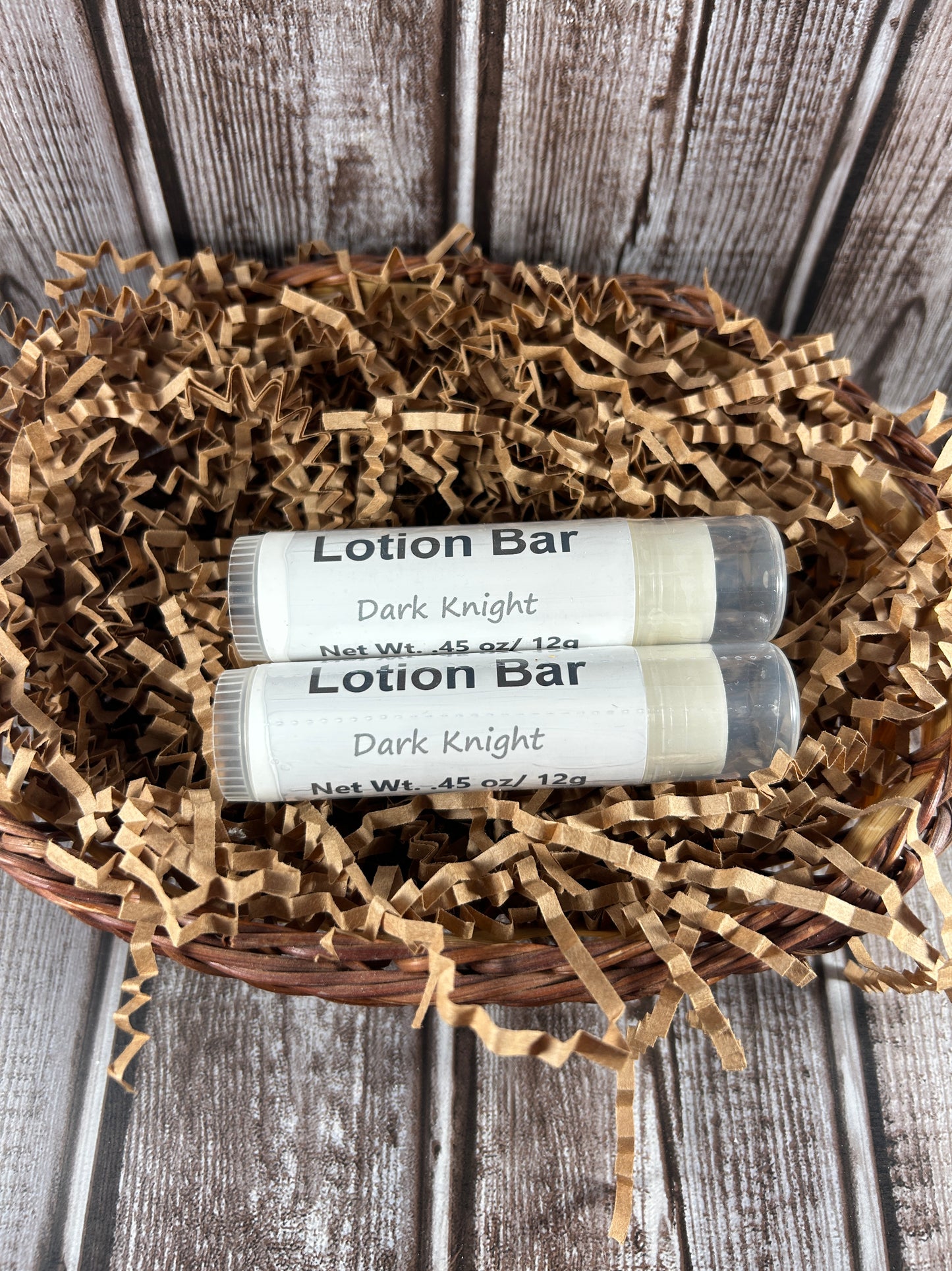Two dark knight scented lotion bars in a decorative basket on a wooden surface